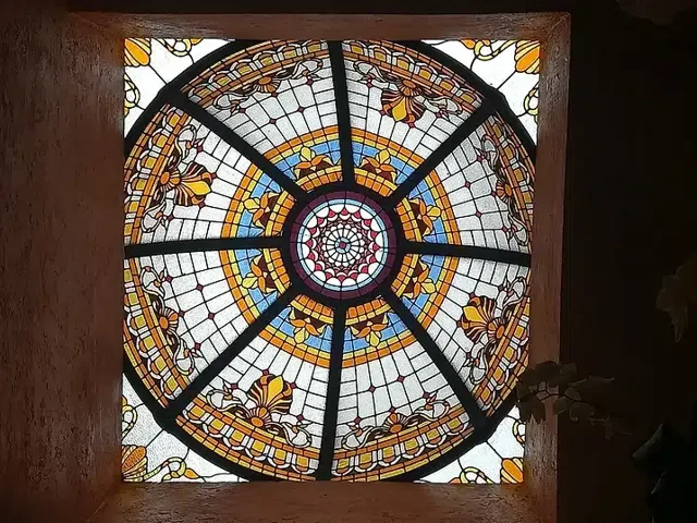 Domo circular de vitral con anillos de colores y estructura radial, visto desde abajo